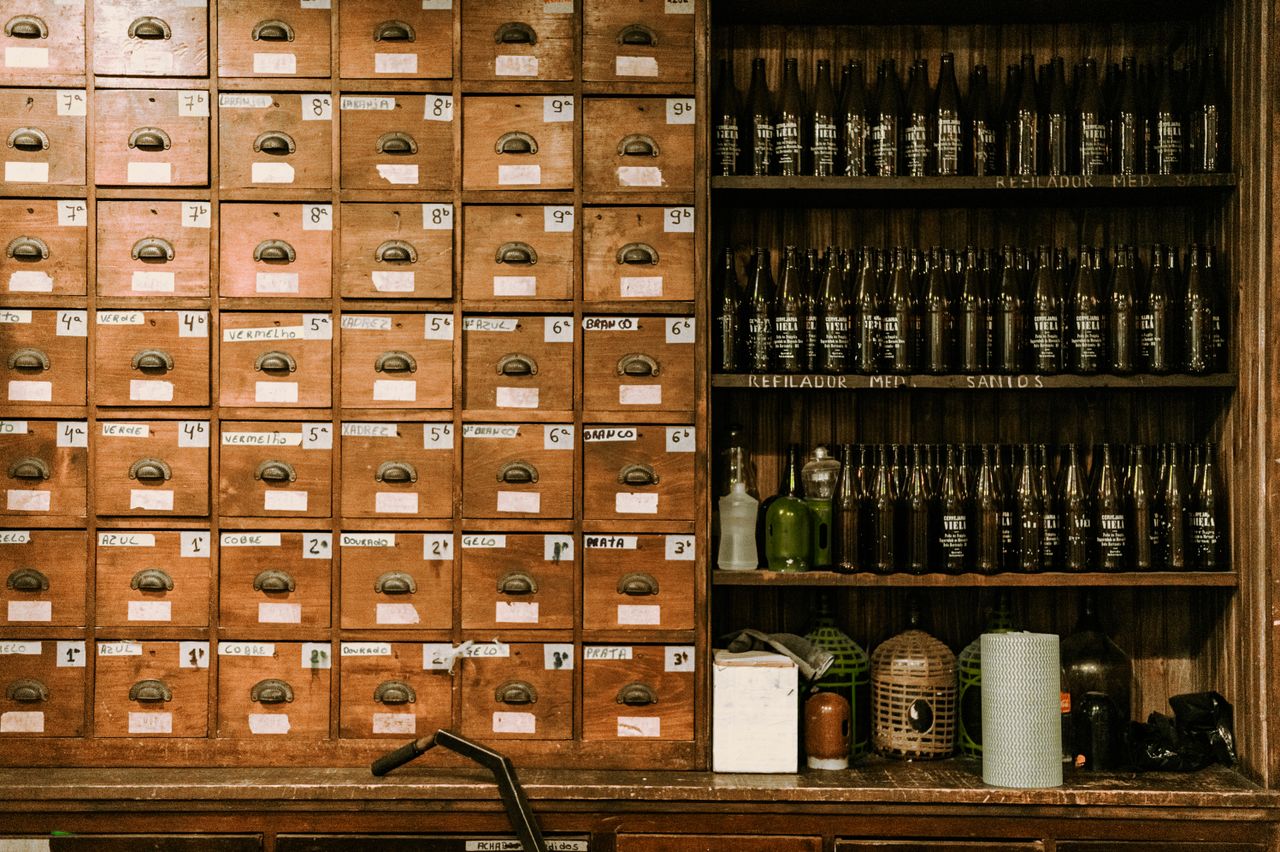 A vintage indoor setup featuring wooden drawers and shelves filled with bottles, evoking a nostalgic mood.